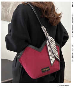 Detail of burgundy velvet tote with V-cut edge and decorative silk scarf on black coat