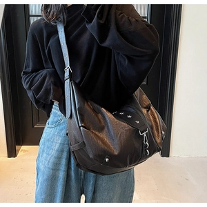 Detail of vintage black faux leather hobo bag with star rivets and wide shoulder strap