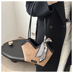 Detail of a brown suede tote bag with black leather trim and a stylish silk scarf handle