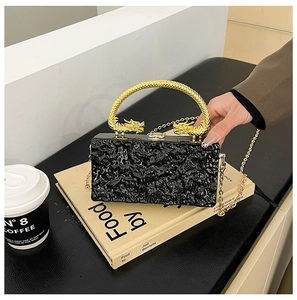 Dettaglio della pochette nera con trama lavica e manici in metallo a forma di drago