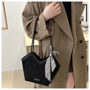 Detail of black suede tote bag with V-cut edge and decorative silk scarf on handle