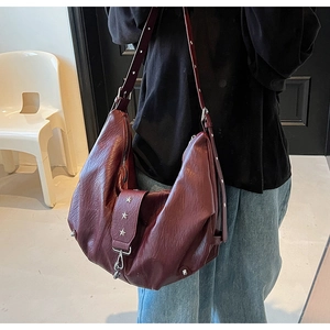 Detail of burgundy leather hobo bag with silver star rivets on adjustable shoulder strap