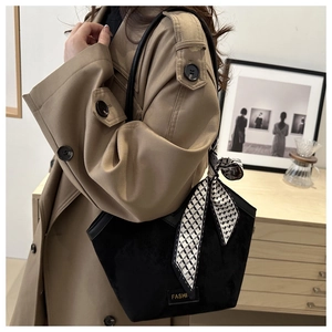 Detail of black matte tote bag with elegant houndstooth scarf on handle and metal tag