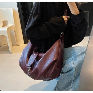 Detail of burgundy pebbled leather bag with silver star studs on the shoulder strap
