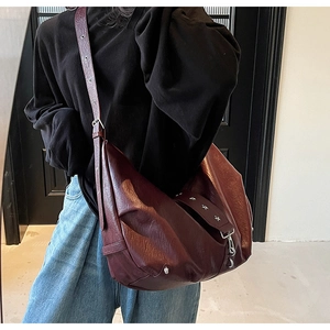 Detail of deep brown crescent tote bag with star rivets and adjustable silver buckle