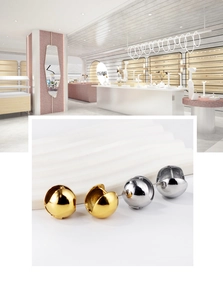Détail de boucles d'oreilles sphériques polies en or et argent sur un support texturé