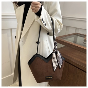 Detailed shot of brown suede tote bag with silk scarf and fashion tag on white coat