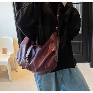 Close-up of deep red crescent tote bag with star detail and adjustable silver eyelet strap