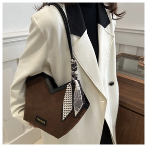 Detail of a brown suede tote bag with V-cut edge, silk scarf and Fashion label