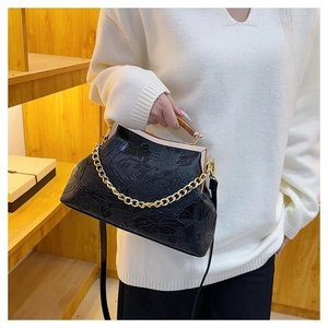 Details der schwarzen Vintage-Tasche mit Koi-Relief und elegantem Holzgriff