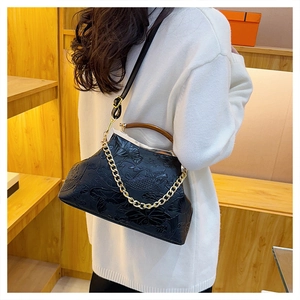 Detail der Vintage-Bügeltasche mit Lotus-Relief und Kette, getragen von einem Modell