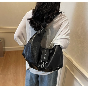 Detail of black crescent shoulder bag featuring silver star rivets and wrinkled texture
