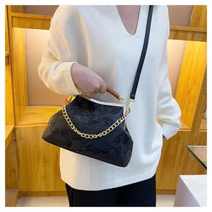 Detail der schwarzen Vintage-Tasche mit Lotus-Prägung, Holzgriff und goldener Kette