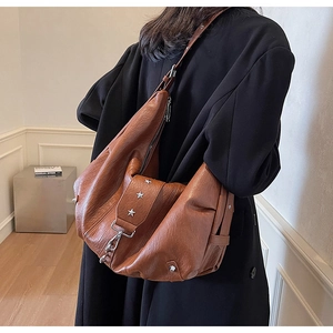 Detail of soft brown leather tote bag with silver star rivets worn with a black blazer