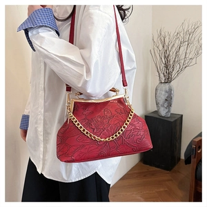 Detailansicht der roten Clutch mit Lotus-Prägung, goldenem Verschluss und Kette