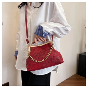 Detailansicht der geprägten Lotusmuster auf einer roten Vintage-Abendhandtasche