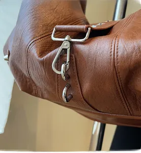 Close-up of silver-tone hardware lock and carabiner on tan leather tote bag