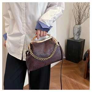 Detail der roten Vintage-Clip-Tasche mit Lotus-Prägung und goldenem Metallgriff