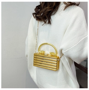 Dettaglio della pochette dorata con manico a dragone e trama a strisce orizzontali eleganti