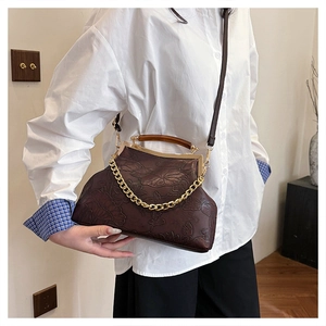 Detail der dunkelbraunen Vintage-Abendtasche mit geprägtem Lotusmuster und Holzgriff