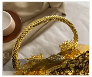 Dettaglio della borsa da sera dorata di lusso con manico decorato a forma di drago