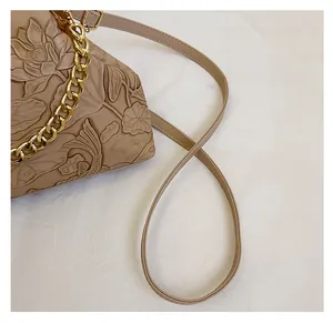 Detailansicht der beigen Abendtasche mit 3D-Prägung von Lotusblumen und Kois