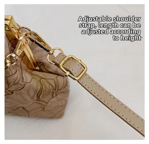 Detail eines verstellbaren Schultergurts und goldener Beschläge an Prägeledertasche