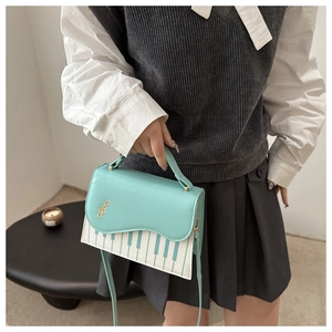 Détail du sac à bandoulière piano vert menthe et blanc avec clé de sol dorée
