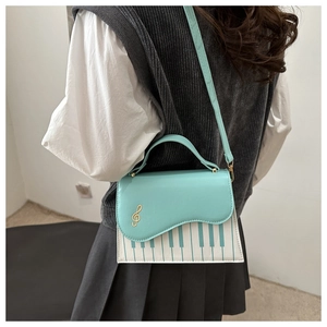 Détail du sac piano vert menthe avec bouton clé de sol et motif de touches de piano