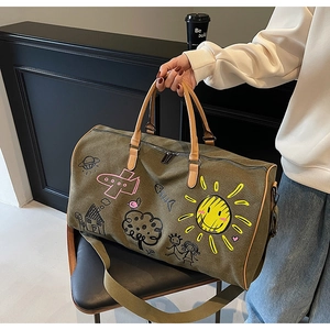 Detail of olive green canvas travel bag with colorful graffiti art and sturdy handles