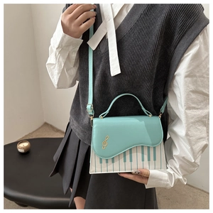 Détail du sac bandoulière vert menthe avec motif clavier de piano et clé de sol dorée