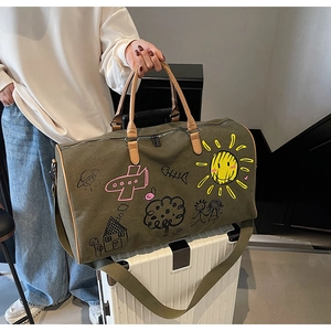 Detail of olive green canvas travel bag with playful doodles and brown leather handles