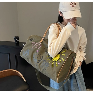 Olive green canvas travel bag with colorful doodle art and premium brown leather handles