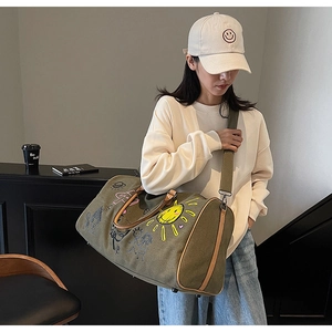 Olive canvas travel bag featuring colorful hand-drawn graffiti and leather handles