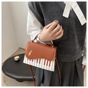 Détail du sac bandoulière touches de piano avec note dorée et bandoulière en cuir