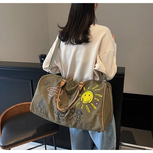 Olive green travel bag with cartoon graffiti and leather handles shown on shoulder