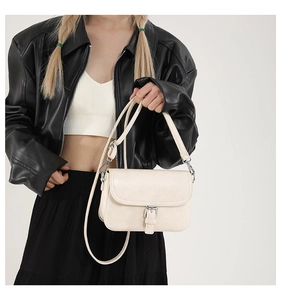 Détail du sac carré crème avec boucle argentée et bandoulière réglable sur le côté