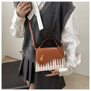 Détail du sac à bandoulière avec motif de touches de piano et fermoir clé de sol doré