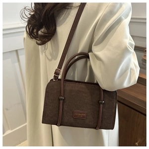 Close-up of brown corduroy handbag texture with leather strap and metal buckle