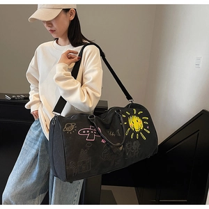 Detail of black canvas travel bag with yellow sun graffiti print and adjustable strap