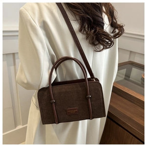 Close-up of brown corduroy crossbody bag texture and leather label on white coat