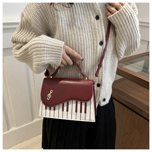Detail of piano key pattern on vintage burgundy crossbody bag with gold treble clef