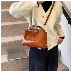 Detail of brown crocodile pattern bucket bag with gold clasp shown on model