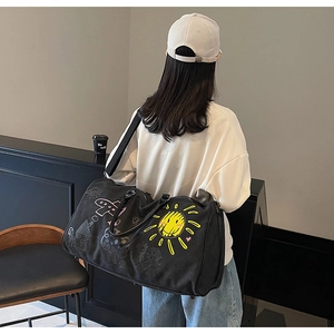 Detailed view of black travel bag with yellow sun and aircraft graffiti patterns