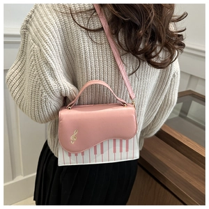 Vue détaillée du sac à bandoulière rose à motif piano porté avec un pull en maille