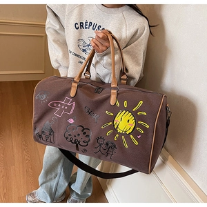 Detail of canvas travel bag featuring colorful artistic graffiti and leather handles