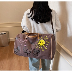 Deep brown canvas duffle bag with colorful doodles and adjustable shoulder strap