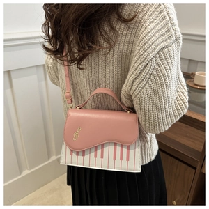Detail of pink piano key handbag with gold music note buckle shown on a model