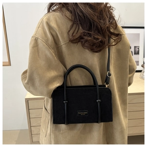 Woman in khaki coat styling the black corduroy crossbody bag with textured stripes