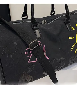Detail of smooth shoulder strap and colorful doodle prints on large black canvas duffel bag